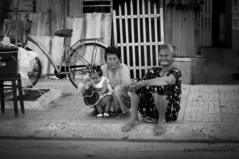 two women with bicycles and a small child on the sidewalk