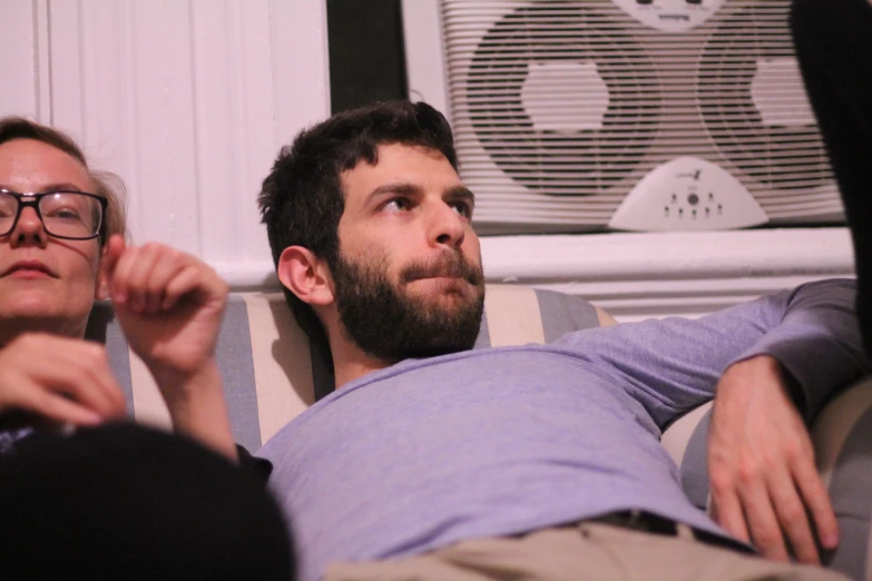 man in grey shirt sitting next to his wife