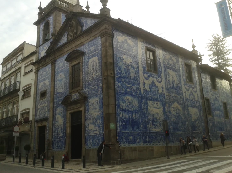 the old building with blue painted paint has some people walking around it