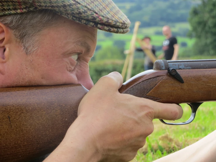 a person with an old hat on shooting a rifle