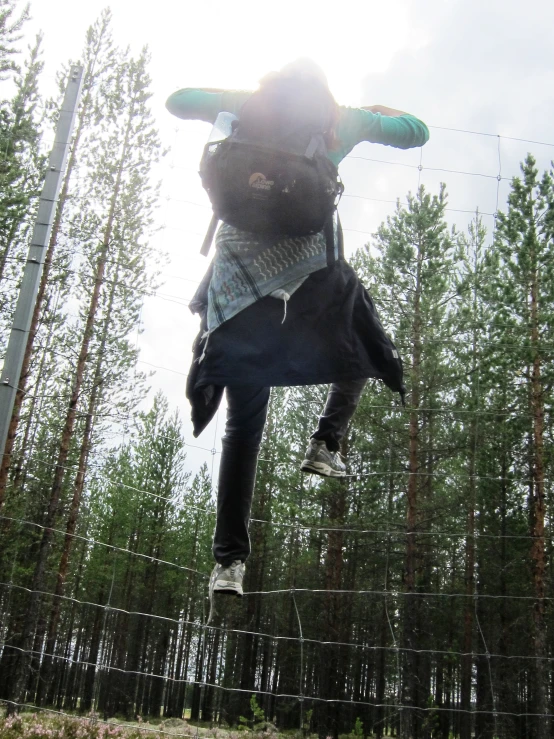 a man doing a flip on a horse in a tree - lined area