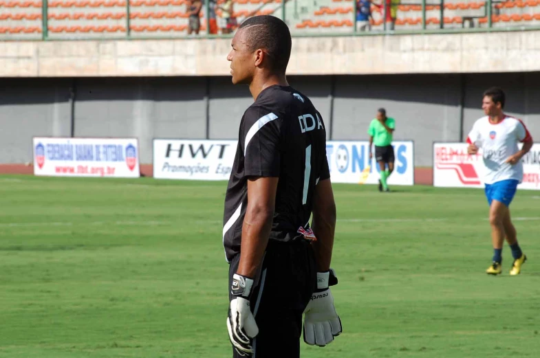 man in black jersey on field wearing gloves
