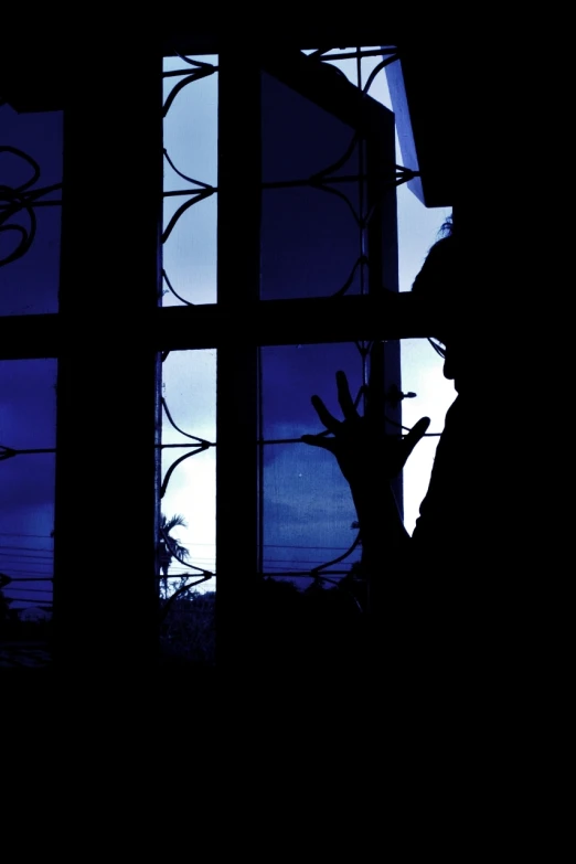 the silhouette of a man looking out the window at a dark sky