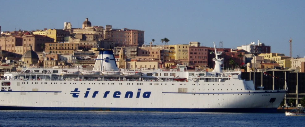 a large cruise ship in a body of water with city skyline in background