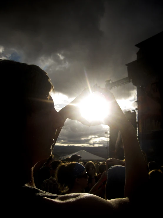 a person is standing under the sun at a concert