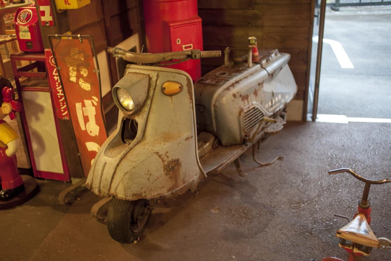 an old, rusty scooter sits in front of a store window