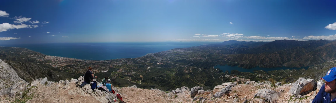 people climbing up a mountain with large lakes in the background