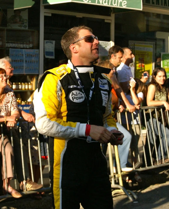 a man wearing a race uniform is standing next to a crowd