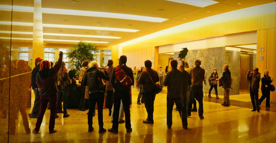 a crowd of people walking down the hall in a lobby