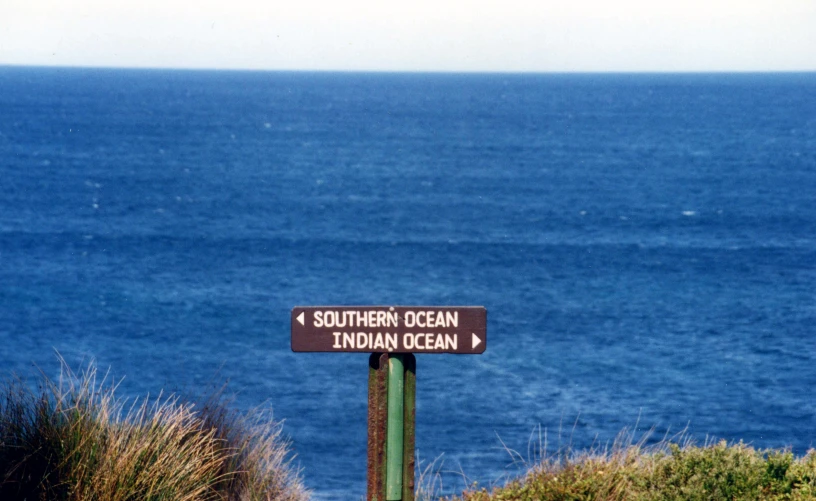 a sign with some words on it by the ocean