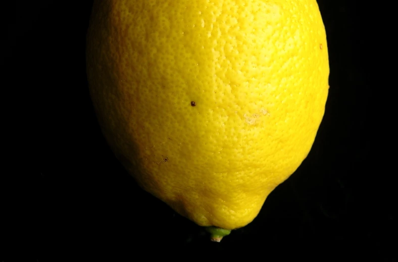 the end of a large yellow lemon against a black background