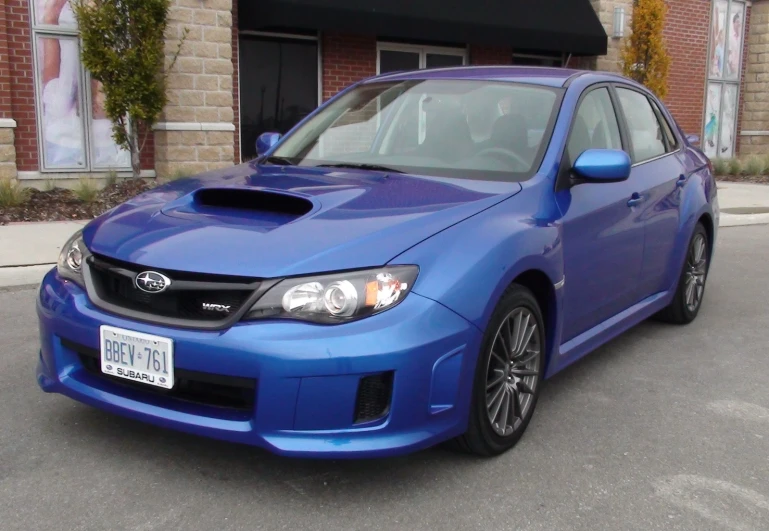 a blue car is parked in front of a brick building