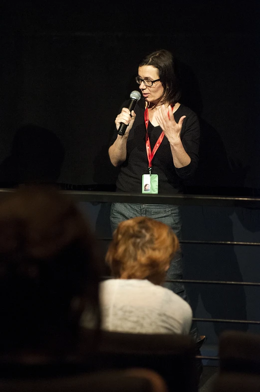 a woman is speaking into the microphone while people are watching