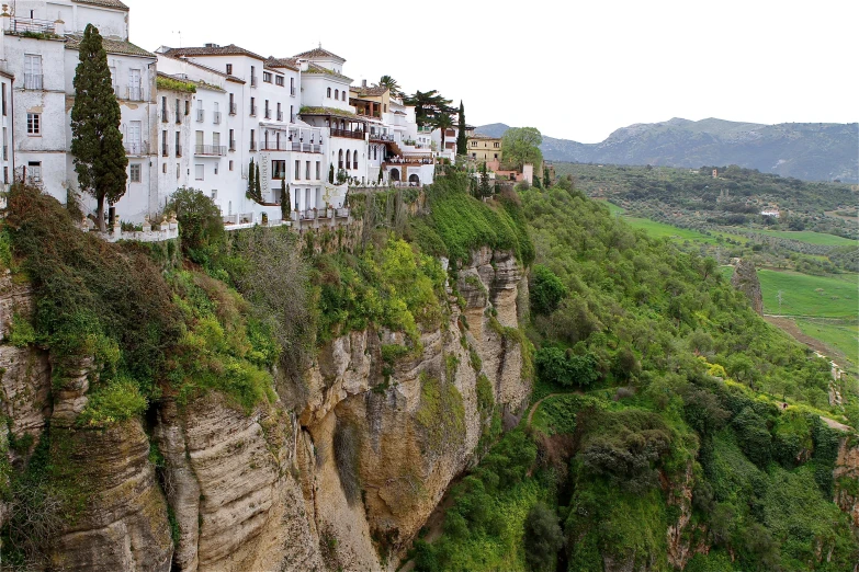 a long row of white buildings on the side of a rocky hill