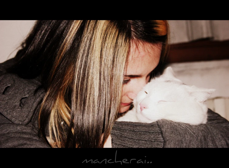 a young lady holding a white cat next to her face