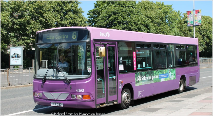 a purple city bus parked in front of a bus stop