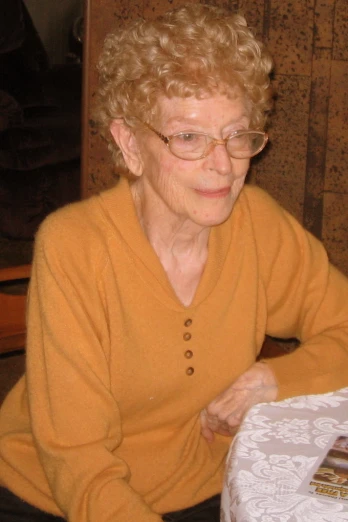 an older woman sitting at a table in front of a white plate