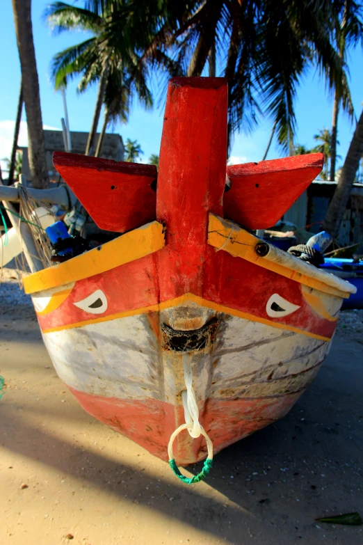 small colorful boat sitting on the sand next to palm trees