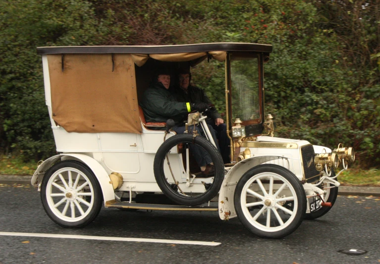 a old model car is driving down the road