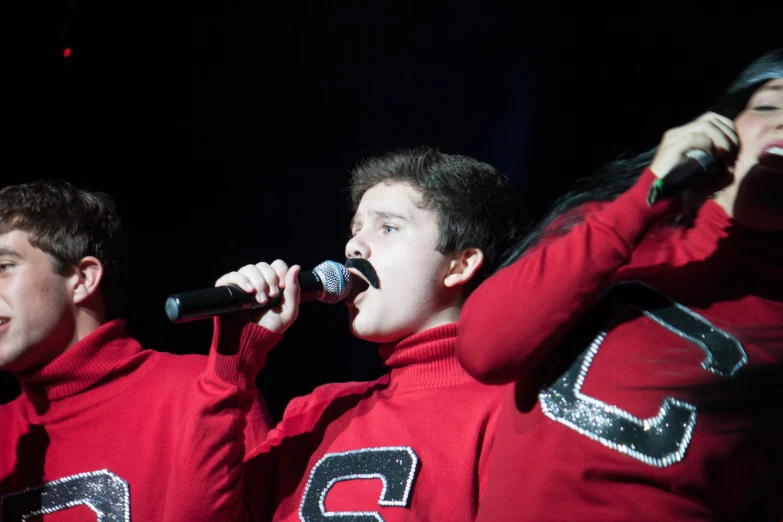 a group of boys are singing into microphones