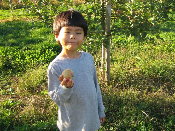 a  in grey shirt standing next to a tree