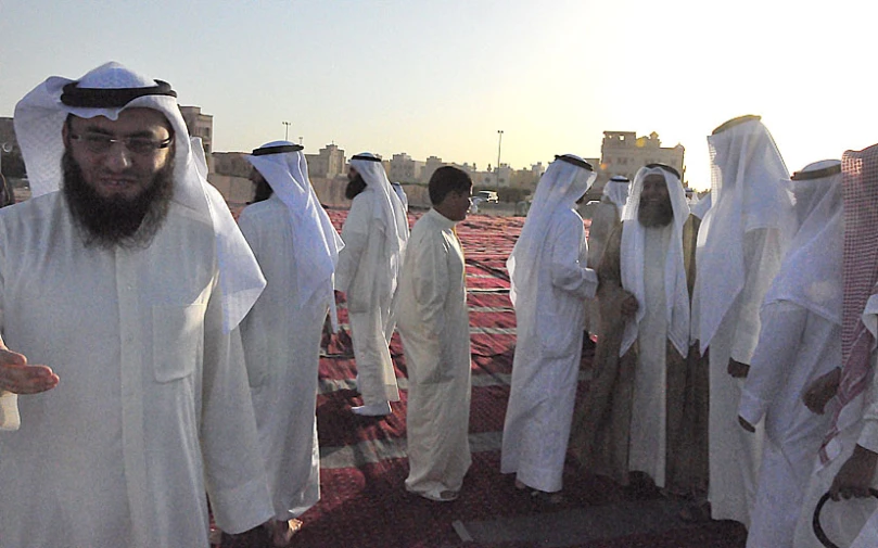 a group of people dressed in white and some with black head coverings
