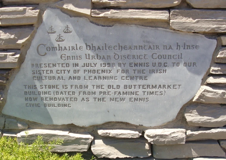 a stone memorial in front of a sign with a building in the background