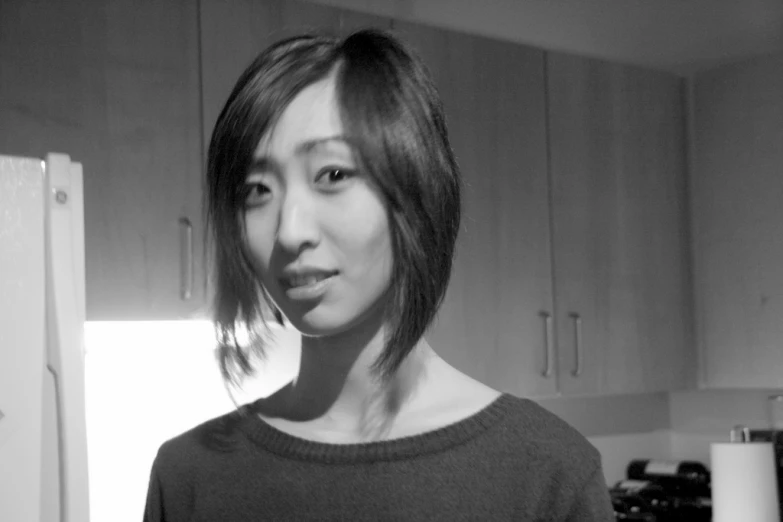 a young woman poses in front of the kitchen refrigerator