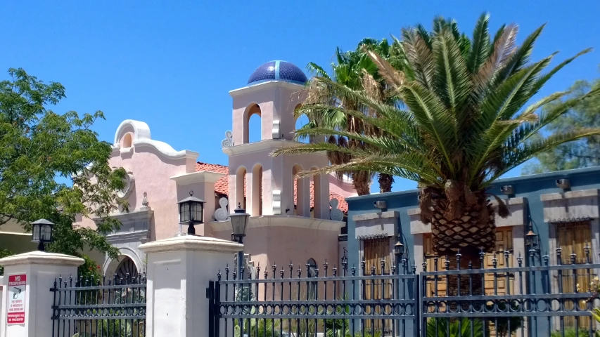 the large church sits near a gate in front of some palm trees