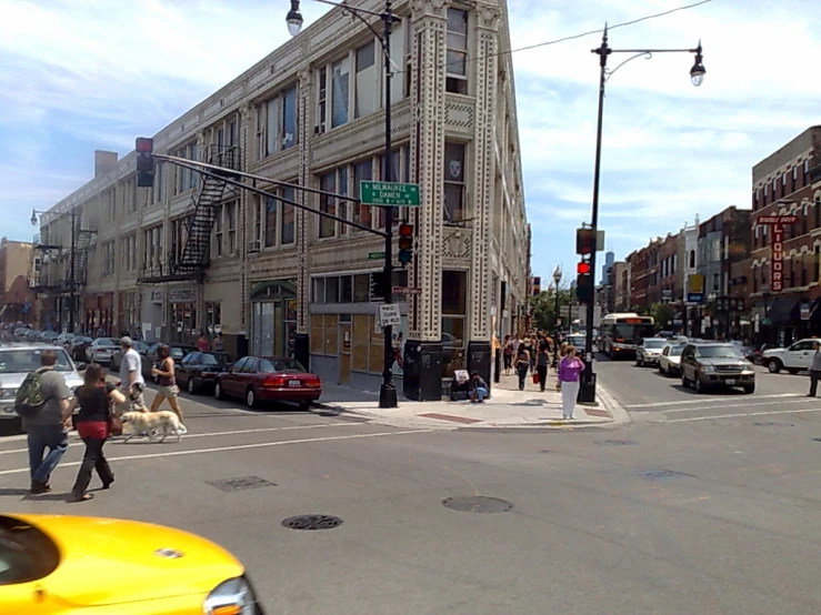 there is a person walking across the street next to a yellow taxi