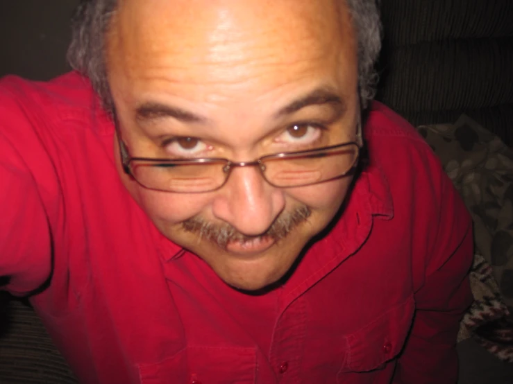 a man in a red shirt and glasses looks at the camera