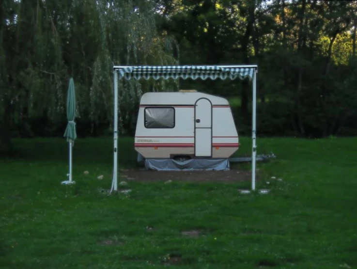 a camper is set up in the backyard with trees