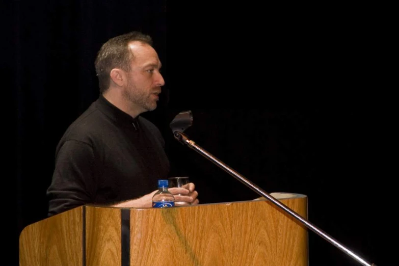 the man is standing at a microphone behind a podium