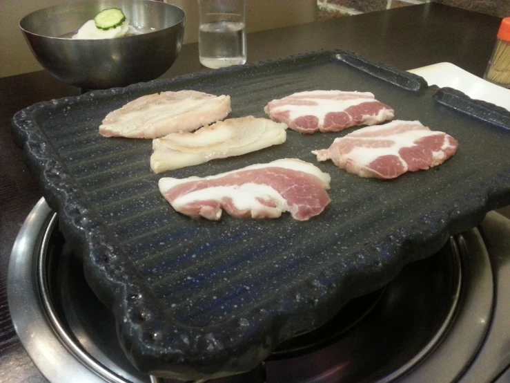 some raw meat sit on a grill cooking