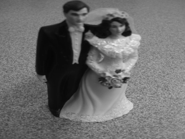 a couple is holding each other close together with the bride and groom figurine in front