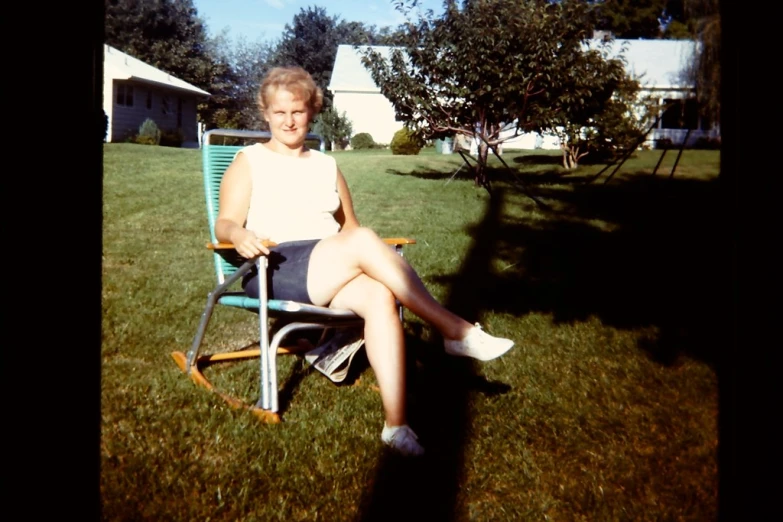 there is a young woman sitting in a chair on the grass