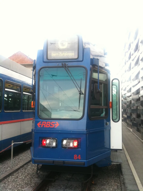 two blue buses sitting next to each other on the tracks