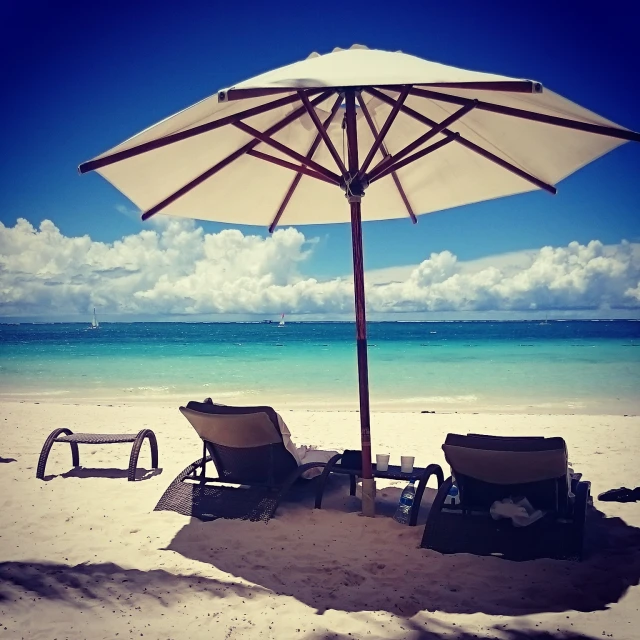 two lawn chairs sitting under a big umbrella