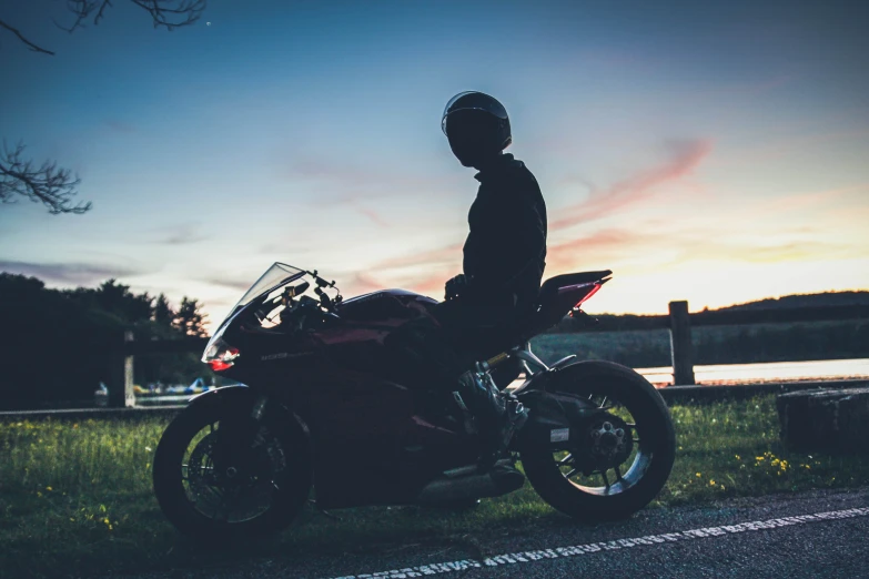 a person standing behind a red motorcycle parked in grass