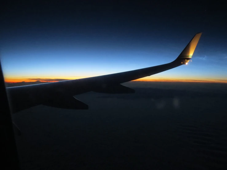 an airplane wing at night with the moon shining