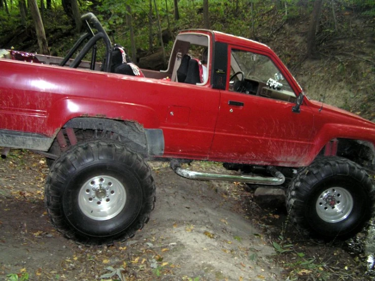 there is a red truck with its large tires on the ground