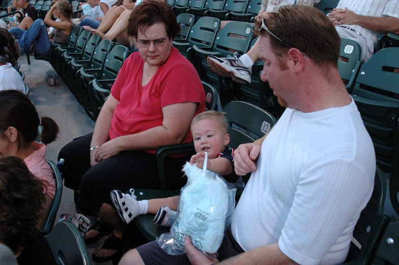 a woman and a baby sit in a stadium as the others watch