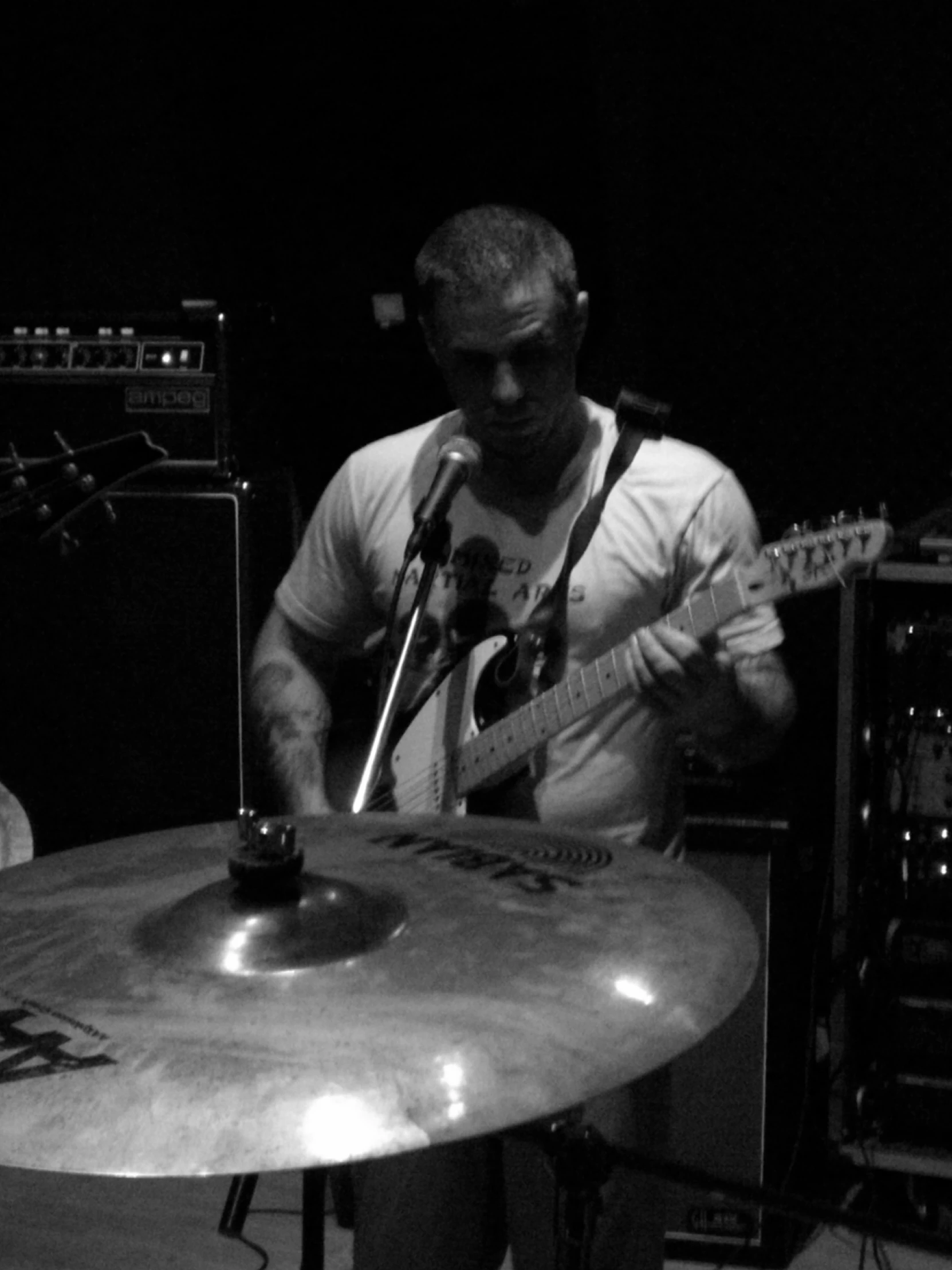 a man sitting in front of a drum kit while holding a guitar