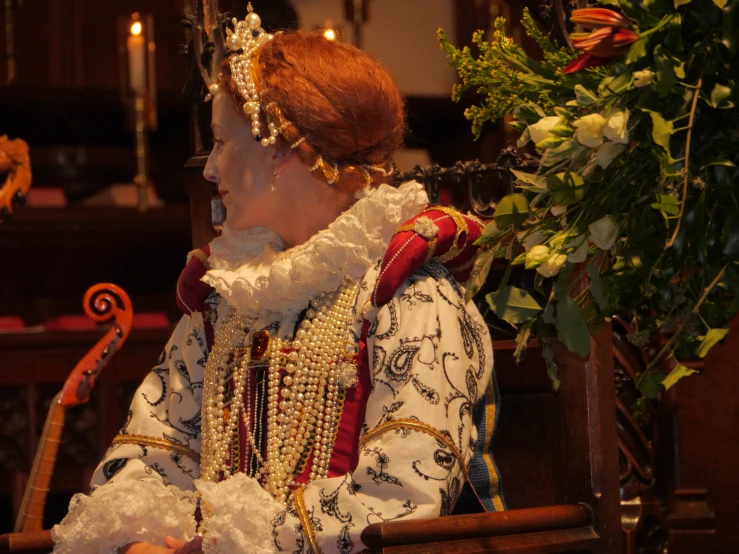 an older lady sitting in a chair wearing a tiara