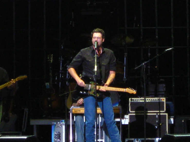 a man sitting on stage playing guitar