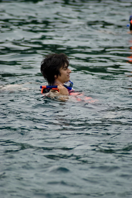 young man enjoying swimming in calm water with other swimmers