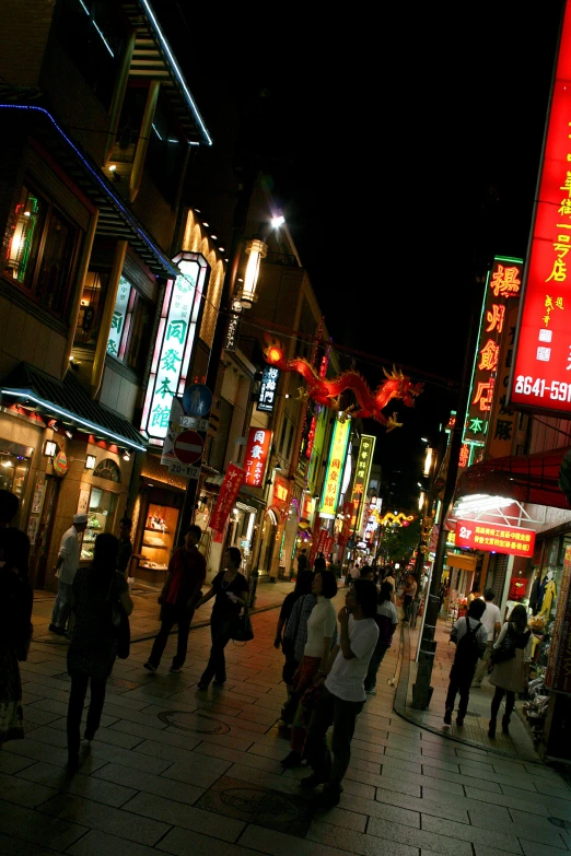 a crowded street with pedestrians at night on the sidewalk