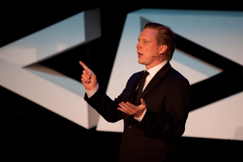 a man in suit and tie speaking into microphone