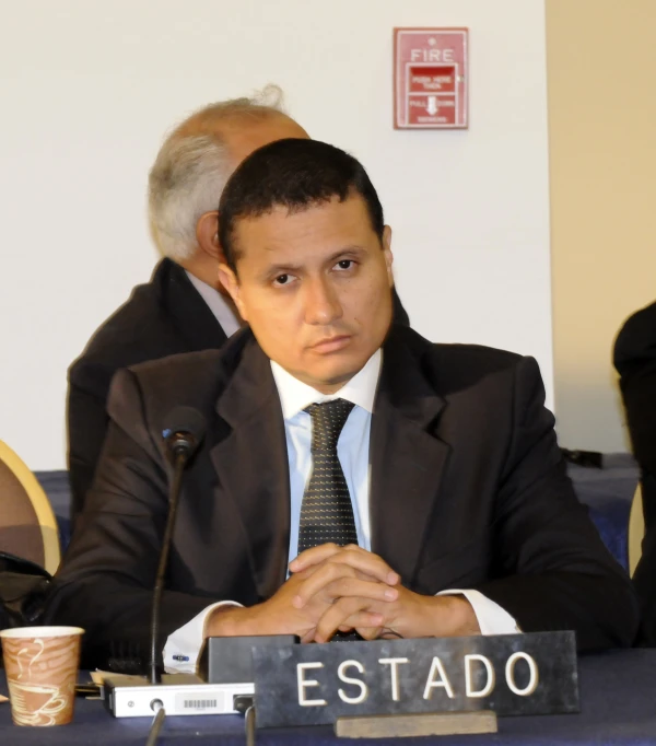 a man sitting in a chair with his hands folded on the table