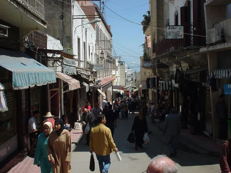 several people are walking down a sidewalk in a small city